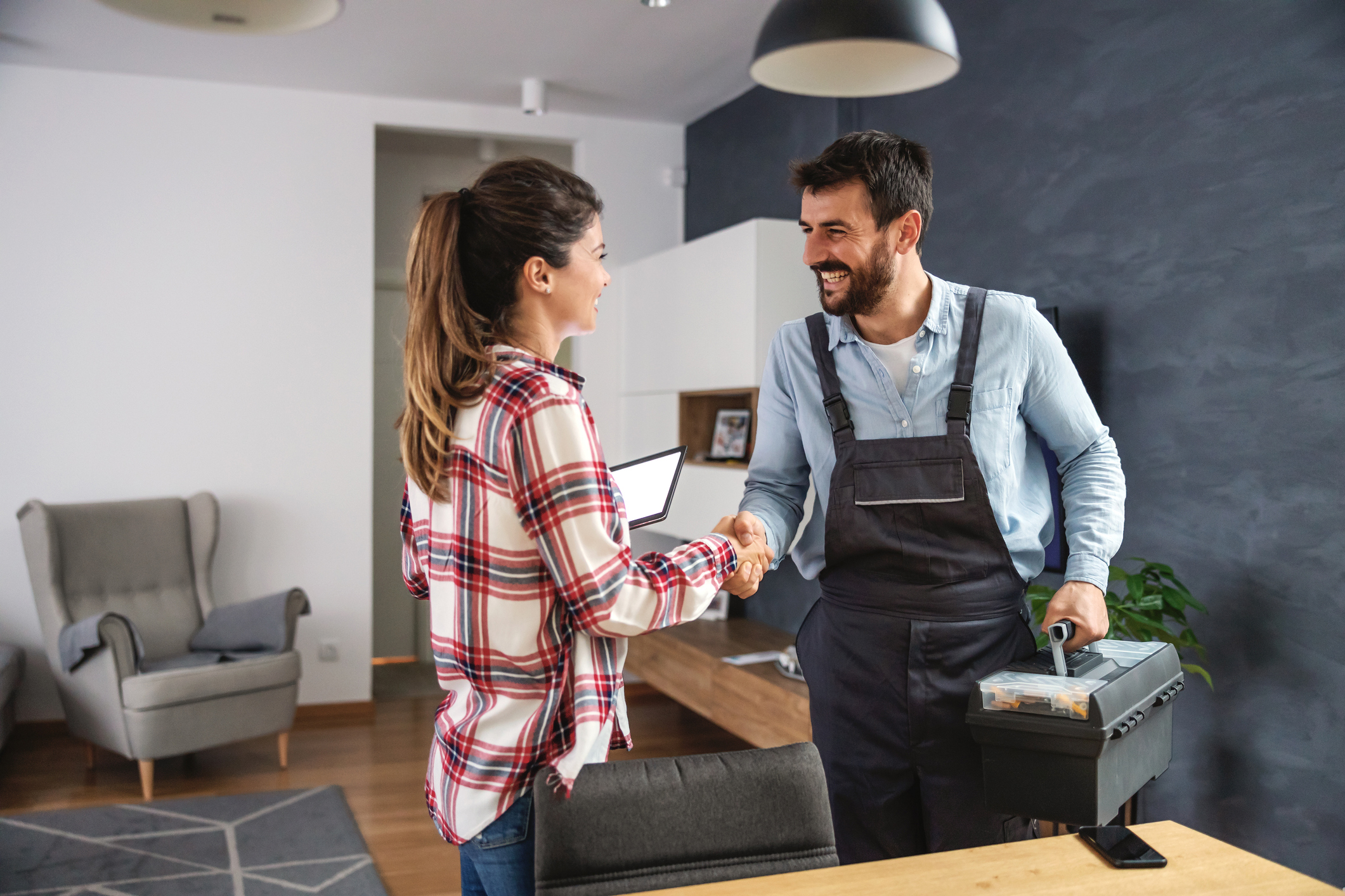 Happy woman shaking hands with repairman. Home interior.